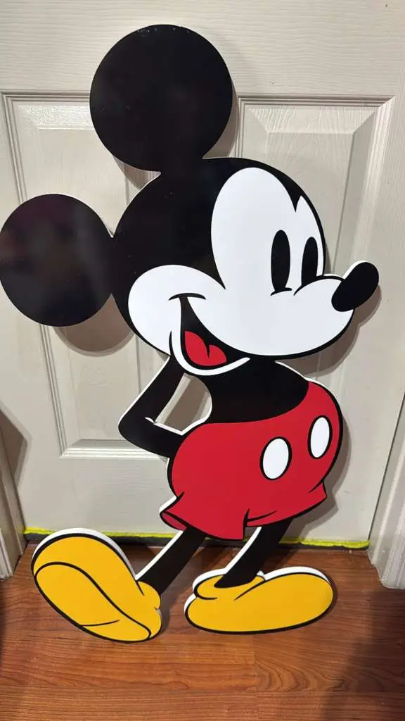 Life-size cartoon mouse cutout in printed PVC leaning against a door
